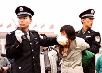 Two Chinese police officers arrest a Falun Gong practitioner at Tiananmen Square in Beijing on Jan. 10, 2000. (Chien-Min Chung/AP Photo)