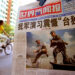 A Chinese cyclist rides by a newspaper with a front page photo featuring the People's Liberation Army (PLA) soldiers in military exercise with the headline "Chinese Military Exercise Frightens Pro-Independence" Aug. 7, 2002 in Beijing, China.(Kevin Lee/Getty Images)