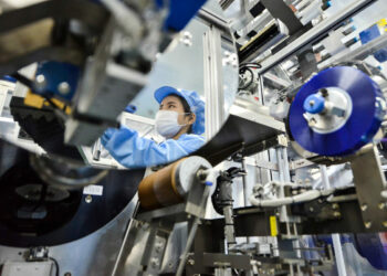 A worker’s reflection on a mirror framing a lithium-ion battery production line at a plant in Huzhou, China, owned by Microvast Holdings, whose Texas-based subsidiary qualified to negotiate for a $200 million U.S. Department of Energy grant to build lithium batteries in the U.S. (Stringer/Reuters)